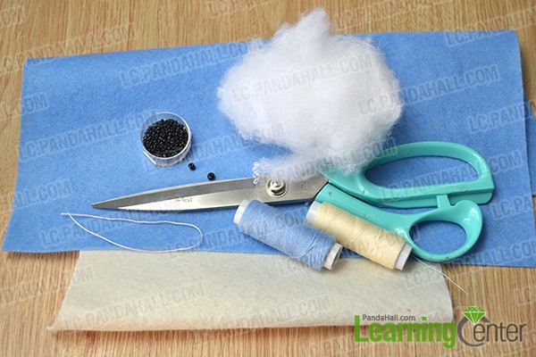 materials and tools for making a blue stuffed dolphin pendant