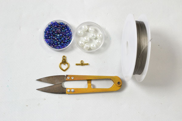 Supplies in making the purple seed bead tassel bracelet with white pearl adornment: