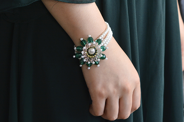 final look of the handmade three-strand white pearl bracelet with green flower